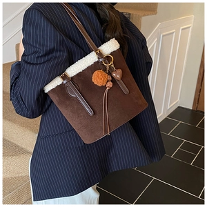 Detail of dark brown matte tote bag with white faux shearling trim and heart pendant