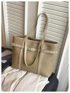 Detail of khaki pebbled leather tote bag with gold rivets and buckle decor