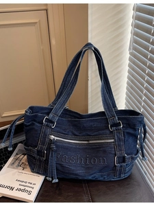 Deep blue denim tote bag with Fashion lettering and side drawstring in a chic urban setting