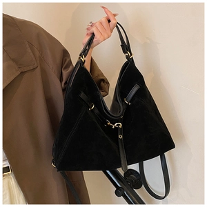 Detail of black suede tote bag with shiny leather straps and gold metal buckle hardware