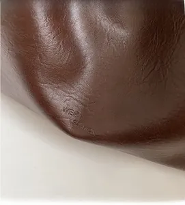 Close-up of deep brown pebbled leather texture with embossed fashion branding logo