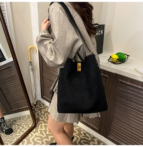 Dettaglio della borsa a secchiello in camoscio nero con fibbia dorata e tracolla in pelle