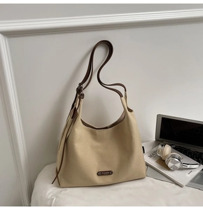Detail of minimalist canvas tote bag with leather strap and metal logo on office desk