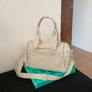 Detail view of large cream nylon travel bag with wide handles and adjustable shoulder strap