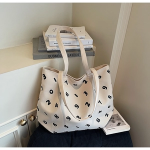 Detail shot of a beige canvas tote bag with black numbers in a lifestyle setting
