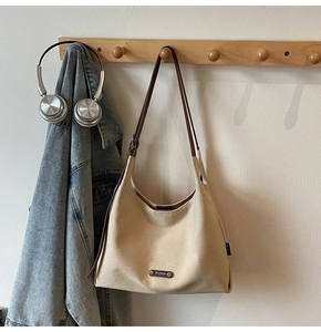 Detail of beige canvas hobo bag with brown leather straps hanging in a lifestyle setting