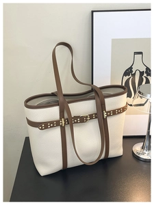 Detail of off-white lychee grain tote bag with brown straps and golden rivets decoration