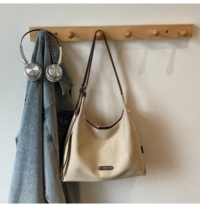 Detailed side view of beige canvas hobo bag with adjustable brown leather strap