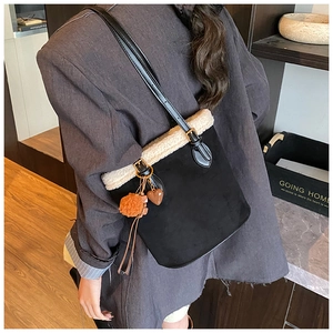 Detail of black suede bucket bag with white fleece trim and heart charm pendant