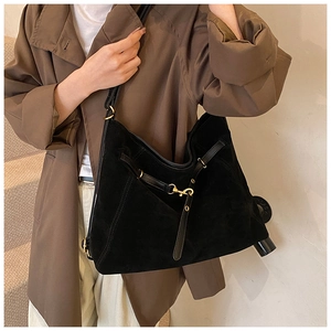 Detail of black suede tote bag with leather straps and gold buckle for daily commuting