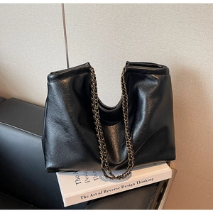 Detail of black glossy PU leather tote bag with vintage bronze chain shoulder straps