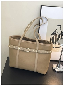 Close-up of khaki pebbled leather tote bag with elegant gold studs and metal buckle detail