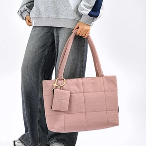Detail of pink quilted tote bag with matching square charm and large grid texture
