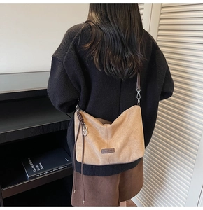 Detail view of khaki suede tote bag featuring brown leather trim and metal hardware