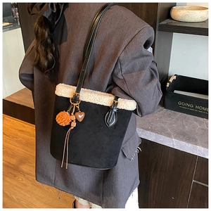 Detail of black suede bucket bag with cream shearling trim and plush heart charms