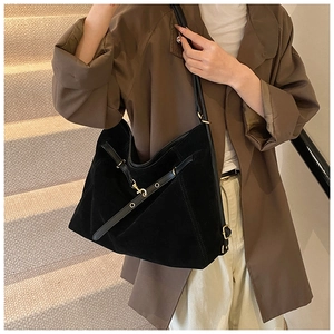 Detailed side view of a large black suede hobo bag with vintage buckle strap and stitching