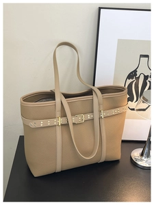 Close-up of khaki tote bag featuring lychee grain leather and gold buckle hardware