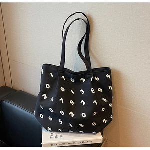 Detail of black canvas tote bag featuring minimalist white numeric print and slim straps