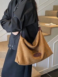 Large brown suede hobo bag with leather logo patch and slim strap for women