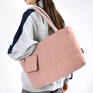 Detailed view of the pink quilted tote bag with a small matching pouch and padded strap