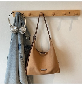 Close-up of a minimalist camel canvas tote bag hanging on a light wood wall rack