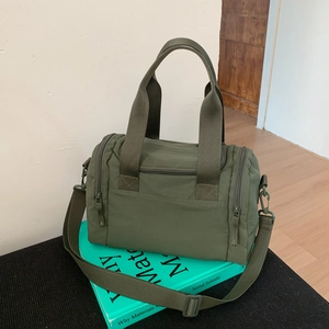 Close-up of military green nylon crossbody tote with durable straps and functional zippers