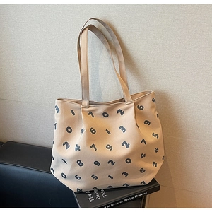 Detail of beige canvas tote bag featuring black numerical prints and dual shoulder straps