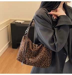 Detailed close-up of leopard print suede bag with silver chain and brand logo