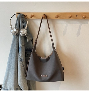 Detailed macro view of dark grey canvas tote with brown leather strap on a wooden rack