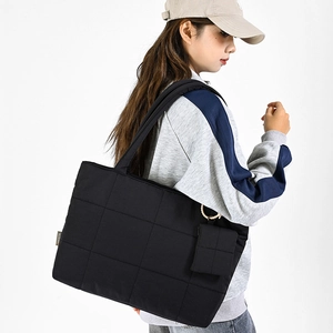Detail of a large black quilted tote bag with matching mini pouch and waterproof nylon fabric