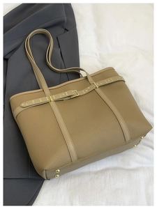 Detail of light brown lychee textured tote bag with gold rivets and protective feet
