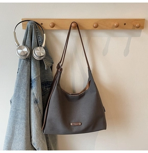 Detail of grey canvas hobo bag with brown leather strap and vintage buckle