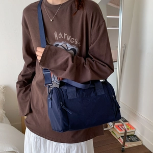 Dettaglio della borsa a cilindro blu navy in tela con tracolla larga in contesto casual