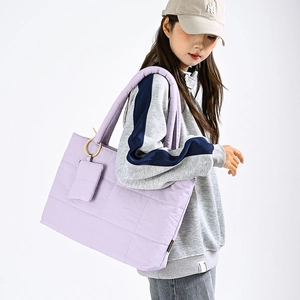 Light purple quilted puffer tote bag with matching square pouch on a casual model