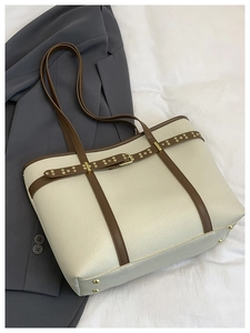 Macro shot of cream lychee texture tote bag with brown leather trim and golden metal studs