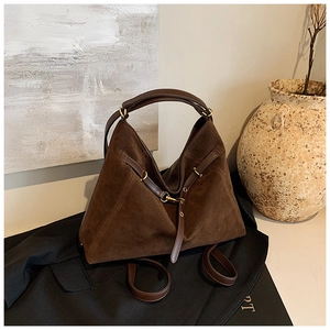 Detail of the dark brown suede tote bag with golden metal hardware and leather straps