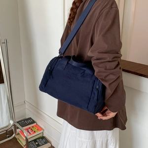 Dettaglio della borsa in tela blu navy con tracolla regolabile e tasca laterale