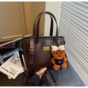 Detail of a dark brown vintage bucket bag with a cute teddy bear charm and gold hardware