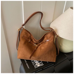 Primo piano della borsa in pelle scamosciata marrone con fibbia dorata su libri di design