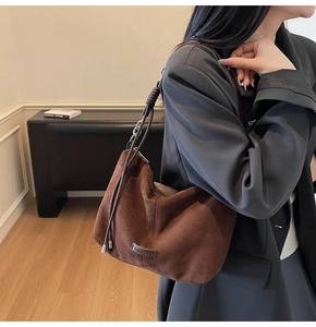 Close-up of brown suede shoulder bag with braided chain strap and metallic logo