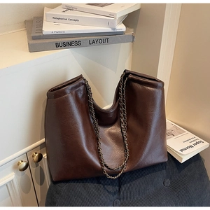 Detail of a dark brown faux leather tote with vintage gold chain strap and soft texture
