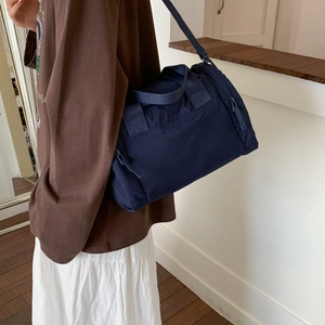 Vista dettagliata di una borsa a cilindro in nylon blu navy con tracolle regolabili
