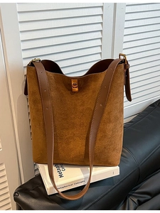 Borsa tote in pelle scamosciata marrone con fibbia dorata su libro e sfondo in pelle nera