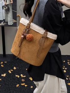 Brown faux suede tote bag with white plush trim and charms on an autumn sidewalk