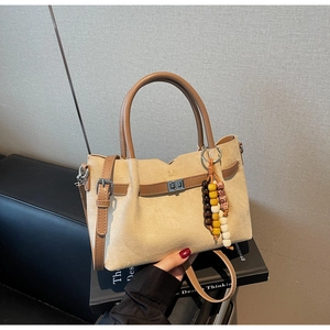 Détail d'un sac seau en daim beige avec breloque en perles de bois et fermoir argent