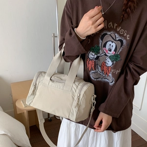 Dettaglio della borsa a cilindro in nylon beige con tasca a zip e trama del tessuto liscia