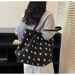 Detail of minimalist black canvas tote with white number prints on shoulder