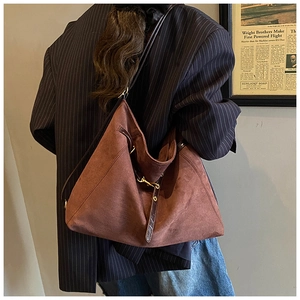 Dettaglio di una borsa tote in pelle scamosciata marrone con fibbia in metallo dorato