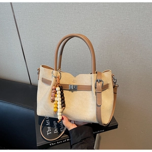 Détail du sac seau en daim crème avec poignée en cuir marron et pendentif en perles bois