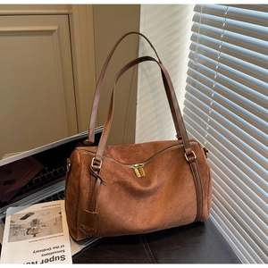 Dettaglio della borsa Boston in camoscio marrone con finiture dorate e tracolla liscia